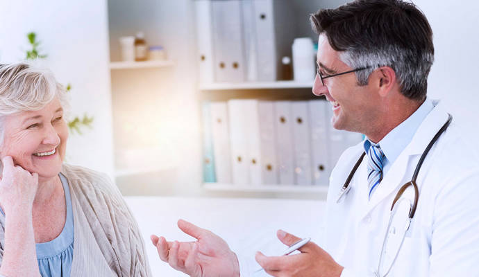 Older female patient smiling with an older male healthcare professional